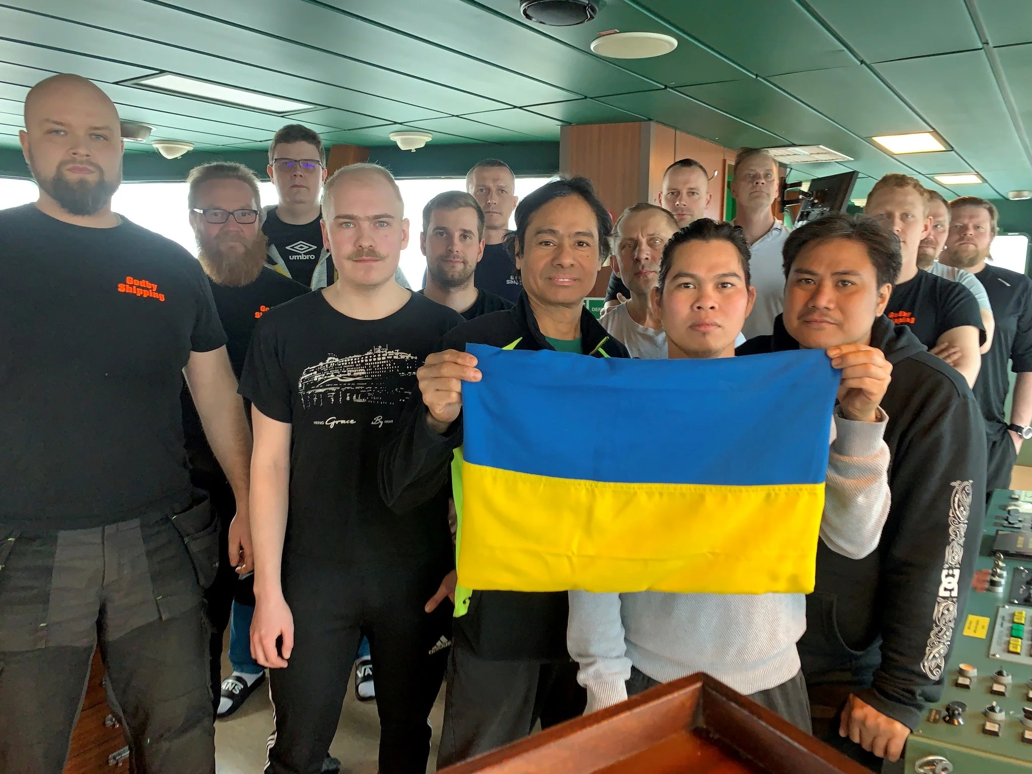 Laivan 15-henkinen kansainvälinen miehistö, etualla olevat pitävät Ukrainan lippua.