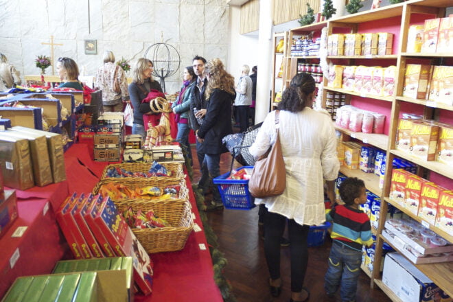 Ihmisiä koreineen tuotehyllyn ja tavarapöydän äärellä.