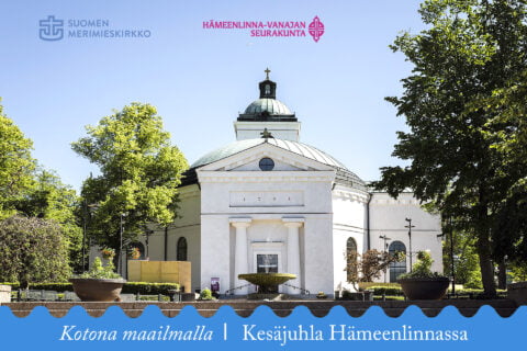Valkotiilinen kirkko lehtipuiden ympäröimänä, alaosassa sininen aaltonauha, jossa teksti Kotona maailmalla - kesäjuhla Hämeenlinnassa.