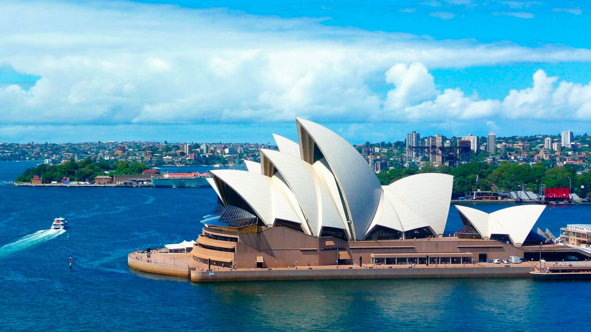 Etualla joki, jonka niemessä valkoinen moderni rakennus ja taustalla kaupungin silhuetti.