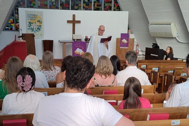 Eri ikäisiä ihmisiä kirkon penkeillä.