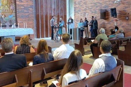 Takana lapsen kastetilanne ja etualla ihmisä kirkon penkeissä.