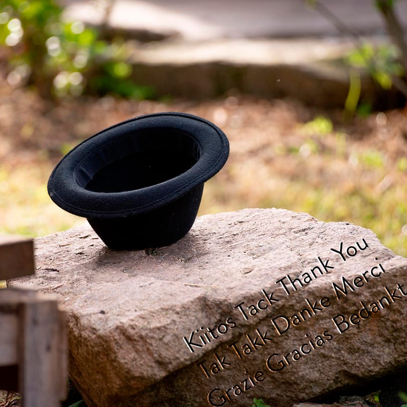 På en rödbrun sten ligger en svart hatt upp och ner, och på stenen står ordet