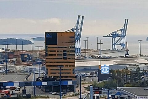 Kuva ylhäältäpäin kohti satamaa ja merta. Keskellä korkea ruskea rakennus.